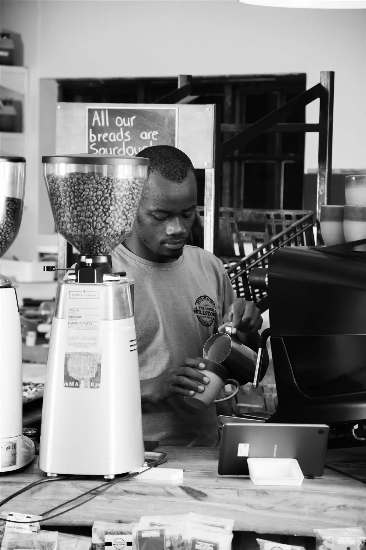 Barista grinding beans behind the counter at The Upper Millstone
